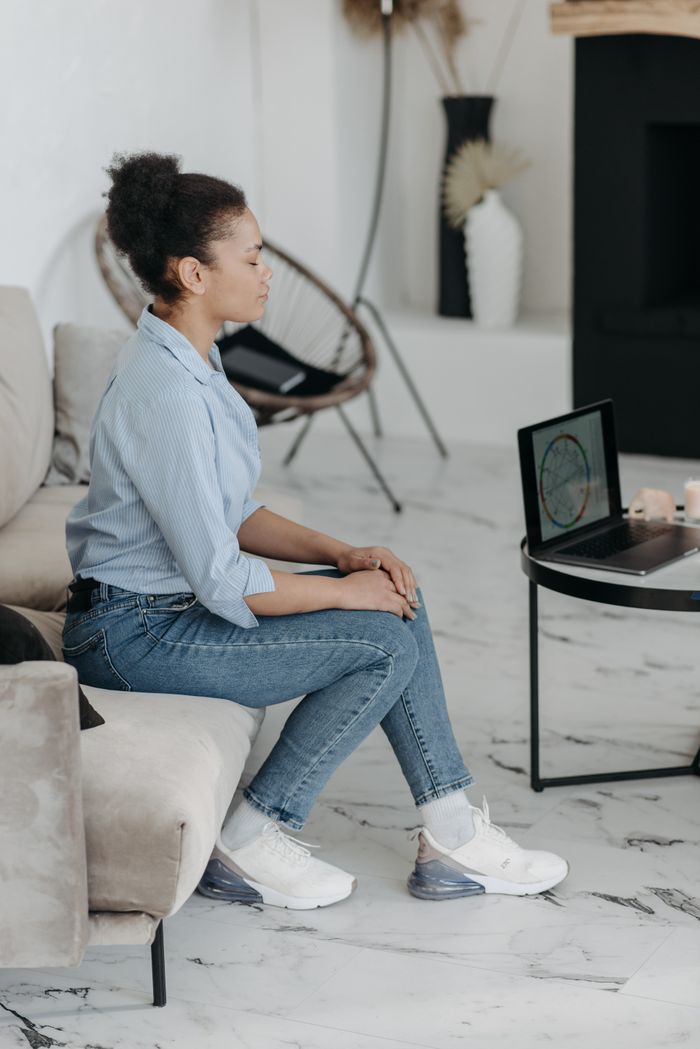 services-01 A woman sits indoors on a sofa, relaxing while using a laptop in a modern living room.